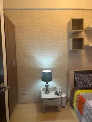 a bedroom with a bed and a table with a lamp at 1 BR Unit at Park West - BGC in Manila