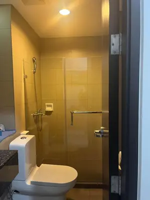 a bathroom with a toilet and a glass shower at 1 BR Unit at Park West - BGC in Manila