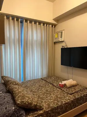 a bedroom with a bed and a flat screen tv at 1 BR Unit at Park West - BGC in Manila