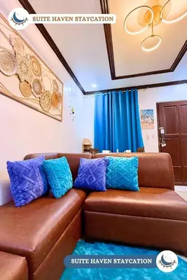 a brown couch with blue pillows in a living room at Suite Haven Staycation in Sampong