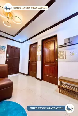 a living room with a couch and two wooden doors at Suite Haven Staycation in Sampong