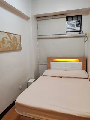 a small bedroom with a bed and a air conditioner at Charming 2BR Condo in Cambridge with WIFI, Smart TV in Cainta