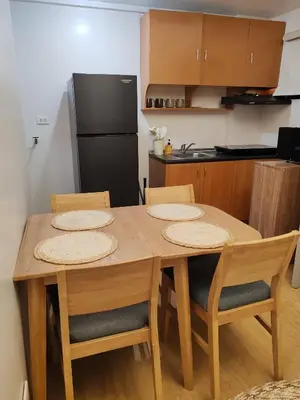 a kitchen with a wooden table with chairs and a refrigerator at Charming 2BR Condo in Cambridge with WIFI, Smart TV in Cainta