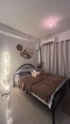 a bedroom with a bed and a lamp and curtains at Shore 2 Residences - The Grand Haven II in Manila