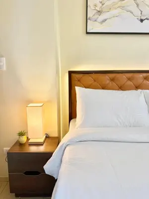 a bedroom with a bed and a nightstand with a lamp at Santis Place at Eighty One Newport Blvd Across NAIA Terminal 3 in Manila