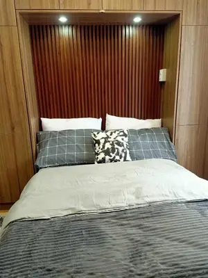 a bedroom with a bed with a wooden headboard at Fully Furnished Condo Near BGC in Manila