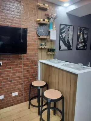 a bar with two stools next to a brick wall at Fully Furnished Condo Near BGC in Manila