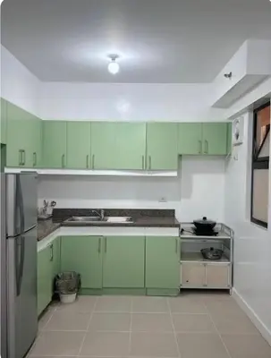 a green kitchen with green cabinets and a refrigerator at Mid-rise staycation in parañaque in Manila