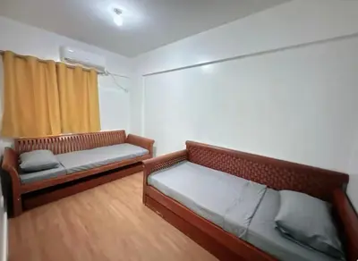 a living room with two beds and a window at Mid-rise staycation in parañaque in Manila