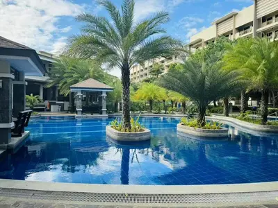 a swimming pool with palm trees and buildings at Mid-rise staycation in parañaque in Manila