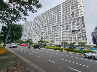 a large building on the side of a road with cars at Shore Residences Sm Mall of Asia Caitlin in Manila