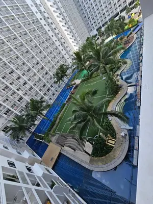 a large building with a swimming pool next to a resort at Shore Residences Sm Mall of Asia Caitlin in Manila