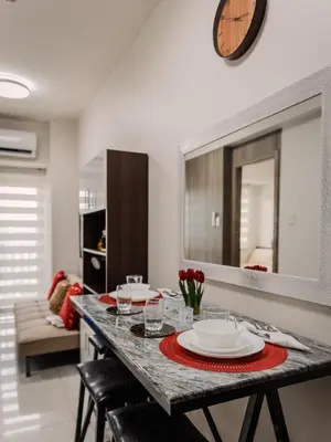 a dining room with a table with chairs and a clock at The Bat Cave 3 at Coast Residences Pasay in Manila