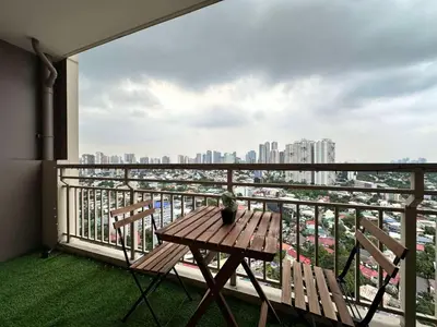 a balcony with a wooden table and chairs and a city at Prisma Residences by Kozy Mood near BGC in Manila