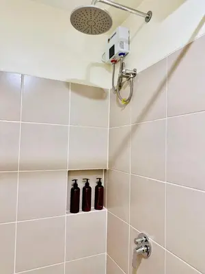a shower with three black bottles in a bathroom at Prisma Residences by Kozy Mood near BGC in Manila