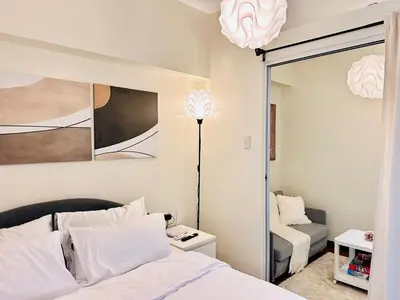 a bedroom with a white bed and a mirror at Prisma Residences by Kozy Mood near BGC in Manila