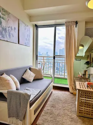 a living room with a couch and a large window at Prisma Residences by Kozy Mood near BGC in Manila