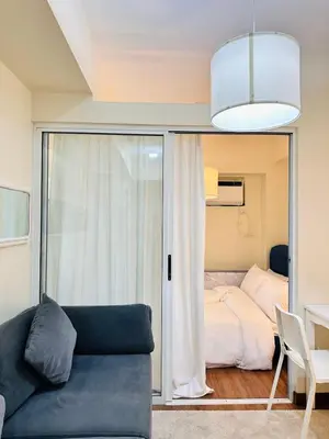 a living room with a couch and a bed at Prisma Residences by Kozy Mood near BGC in Manila