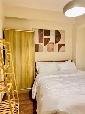 a bedroom with a bed and a wooden cabinet at Prisma Residences by Kozy Mood near BGC in Manila