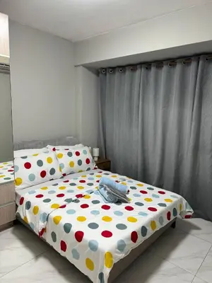 a bedroom with a bed with polka dot sheets at Monarch Parksuites staycation near Moa IKEA Solaire in Manila