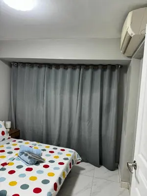 a bedroom with a bed and a gray curtain at Monarch Parksuites staycation near Moa IKEA Solaire in Manila