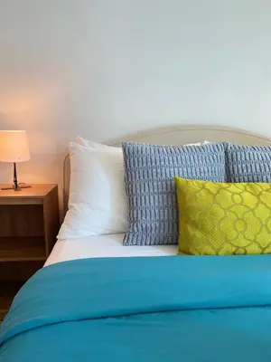 a bed with blue and white pillows and a lamp at Uptown Parksuites Posh Modern Minimalist in Manila