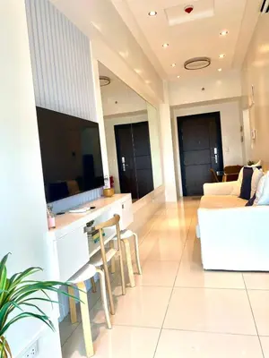 a living room with a white couch and a tv at Uptown Parksuites Posh Modern Minimalist in Manila