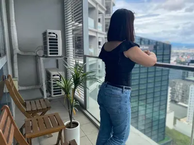 a woman standing on a balcony looking out at the city at Uptown Parksuites Posh Modern Minimalist in Manila