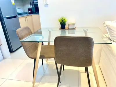 a glass table with two chairs and a plant on it at Uptown Parksuites Posh Modern Minimalist in Manila