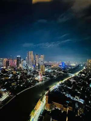 a view of a city at night with a river at RBR LUX at Novotel Manila Hotel Residences Acqua in Manila