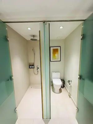 a bathroom with a toilet and a glass door at RBR LUX at Novotel Manila Hotel Residences Acqua in Manila