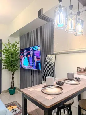 a kitchen with a table and a tv on a wall at Relax in Comfort at Shore 2 Residences Mall of Asia-Pasay in Manila