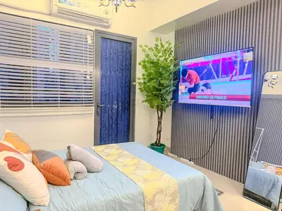 a bedroom with a tv and a bed with pillows at Relax in Comfort at Shore 2 Residences Mall of Asia-Pasay in Manila
