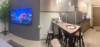 a kitchen with a bar with stools and a tv on the wall at Relax in Comfort at Shore 2 Residences Mall of Asia-Pasay in Manila