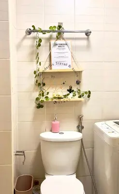 a bathroom with a toilet and a shelf with plants at 1BR Unit for 2 pax Makati City in Manila