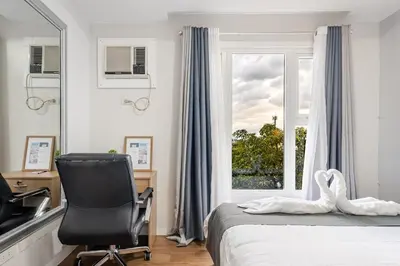 a bedroom with a bed and a chair and a window at Air Bel & Be! Your space, Your calm, Your comfort in Manila