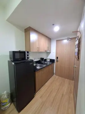 a kitchen with a black refrigerator and a sink at StaycationPH in Manila