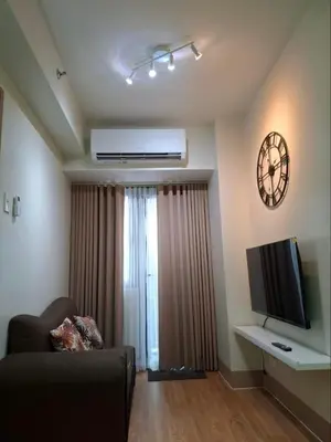 a living room with a couch and a flat screen tv at StaycationPH in Manila