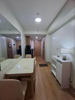 a living room with a table and chairs and a kitchen at StaycationPH in Manila