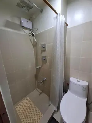 a bathroom with a shower with a toilet and a shower curtain at StaycationPH in Manila