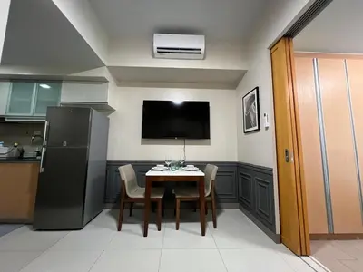 a kitchen with a table with chairs and a refrigerator at 1BR - Uptown BGC Taguig in Manila