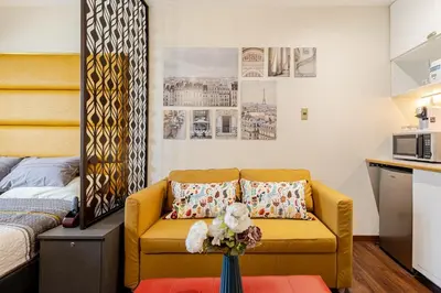 a living room with a yellow couch and a kitchen at Opulent Condo Knightsbridge Residences in Manila