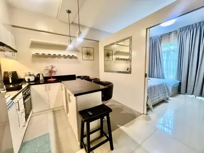 a kitchen with a counter and a table in a room at Casa Ysabella at Stamford, Mckinley Hill in Manila