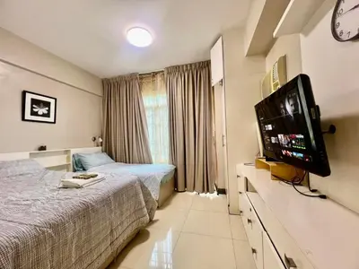 a hotel room with two beds and a flat screen tv at Casa Ysabella at Stamford, Mckinley Hill in Manila
