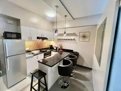 a kitchen with white cabinets and black counter tops at Casa Ysabella at Stamford, Mckinley Hill in Manila