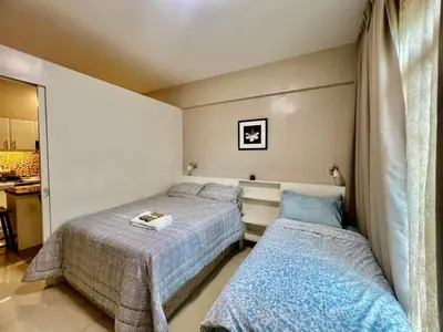 a bedroom with two beds and a kitchen at Casa Ysabella at Stamford, Mckinley Hill in Manila