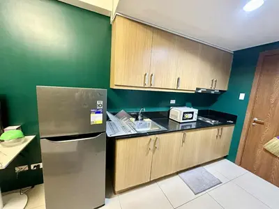 a kitchen with wooden cabinets and a stainless steel refrigerator at Shell Residence MOA Pasay by Kathy in Manila