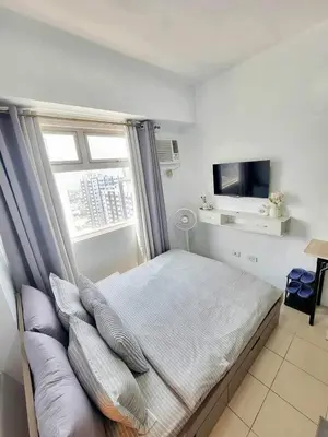 a bedroom with a bed with pillows and a tv at Erro Place Wi-Fi 200mbps & Netflix in Manila