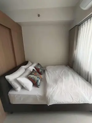 a bed with white sheets and pillows in a room at Red Residences Modern Apartment with City View in Makati in Manila