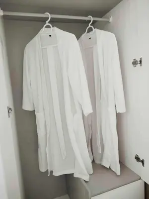 three white shirts hanging on a rack in a closet at Red Residences Modern Apartment with City View in Makati in Manila